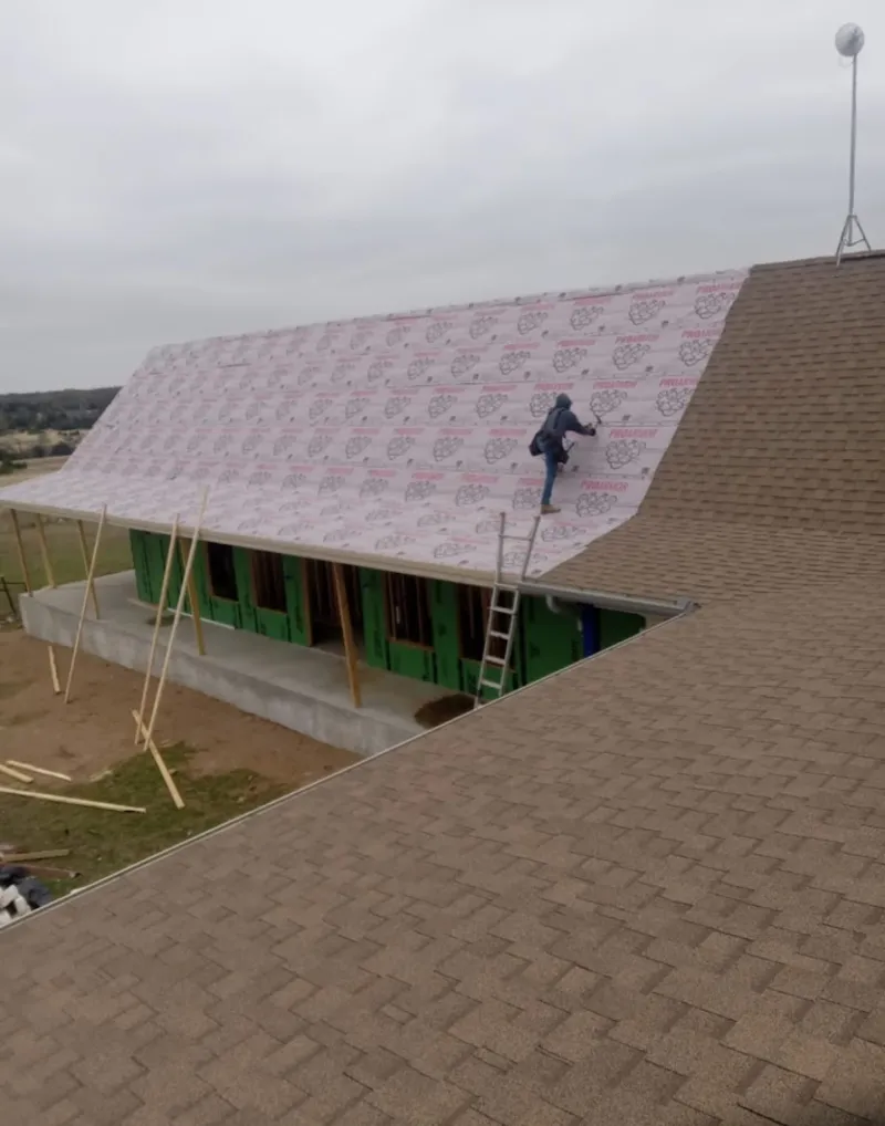 Worker preparing underlayment for a metal roof installation in Albertville